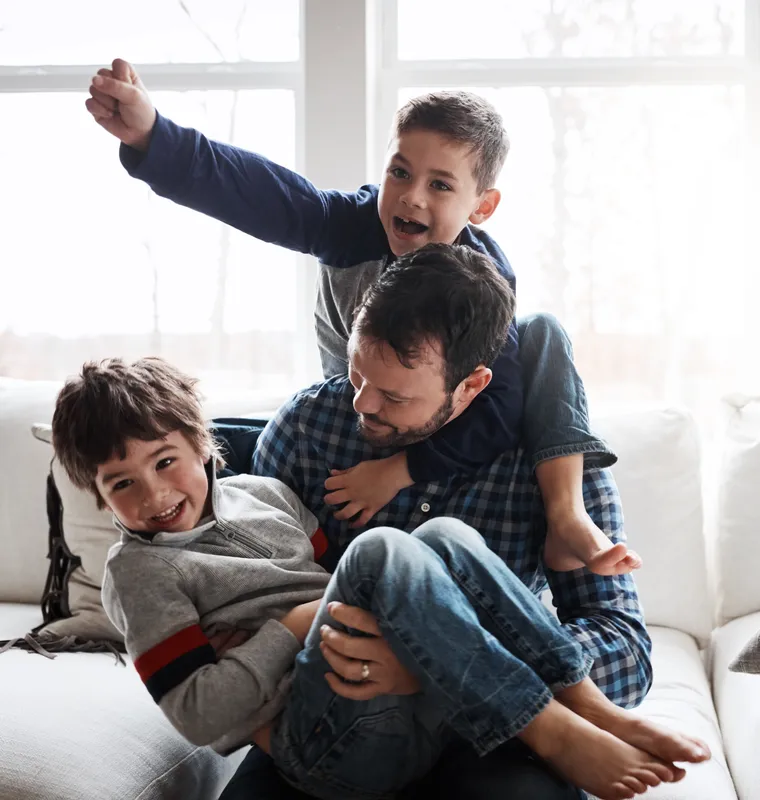 Padre e hijo riendo juntos en el sofá de casa
