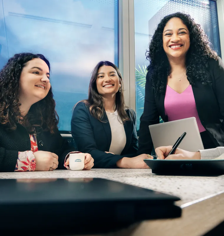 Tres profesionales sonriendo en una reunión de trabajo en la oficina